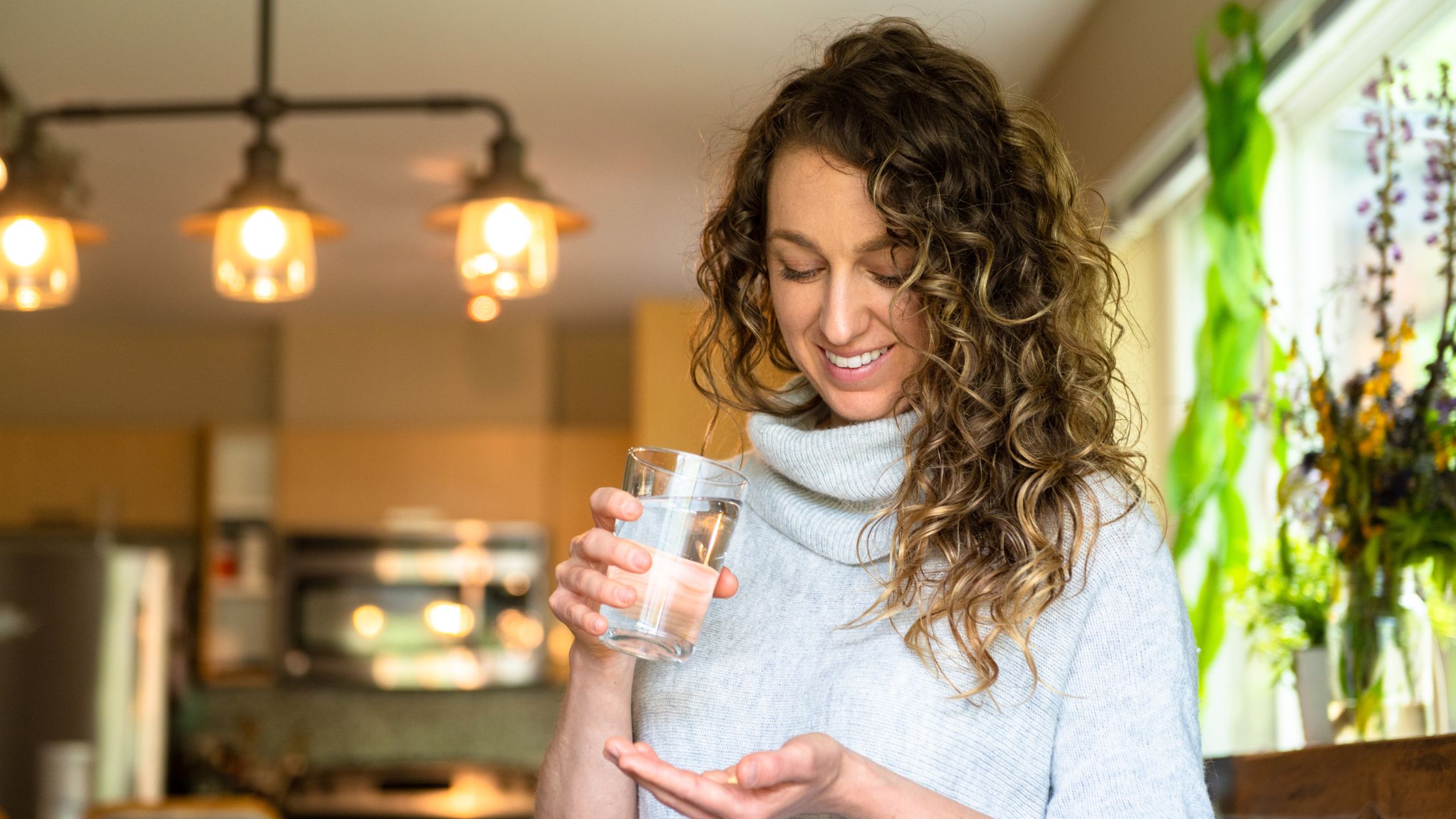 Frau ab 40 hält lächelnd ein Supplement in der Hand
